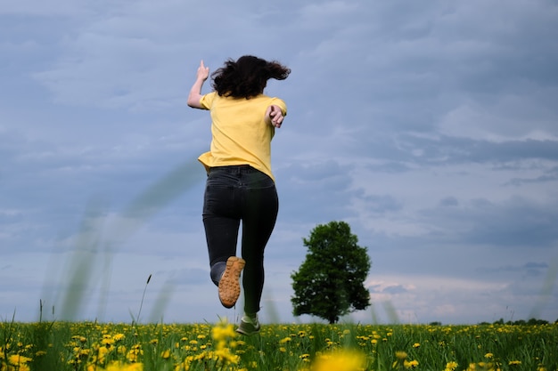 Woman in a yellow t-shirt moves across the field with flowers