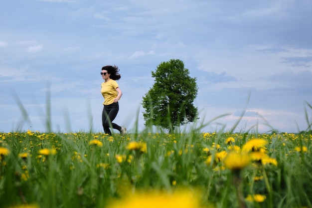Woman in a yellow t-shirt moves across the field with flowers