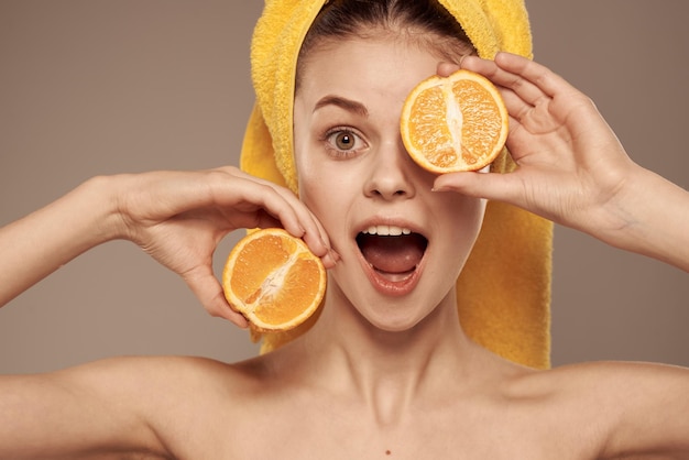 Woman in a yellow towel on her head oranges closeup beige background