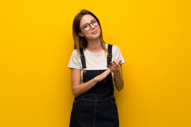 Woman over yellow wall applauding after presentation in a conference