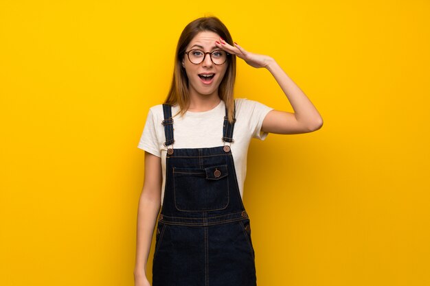 Woman over yellow wall has just realized something and has intending the solution