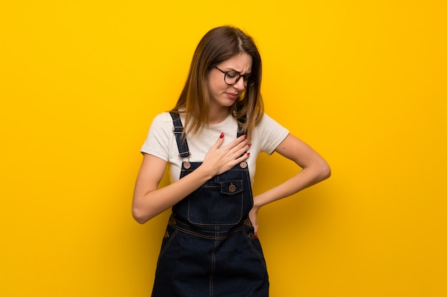 Woman over yellow wall having a pain in the heart