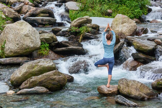 요가 아사 나 Vrikshasana 트리에서 여자 폭포 야외에서 포즈