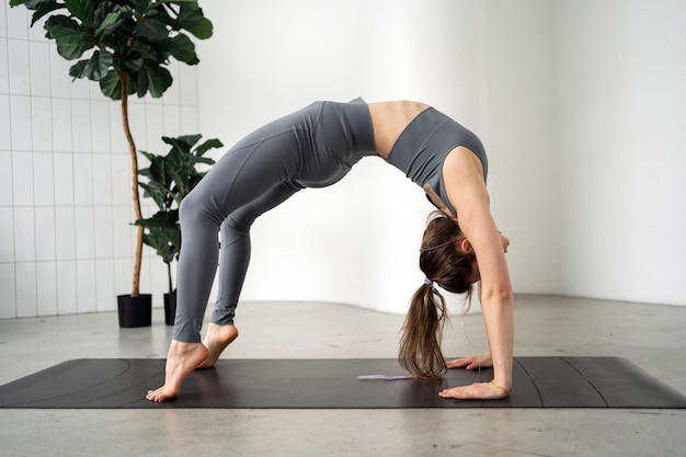 Woman in a yoga bridge pose on a mat demonstrating flexibility and strength in a serene space