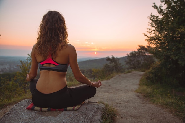 Woman do yoga exercises at top of the hill on sunrise. lifestyle concept