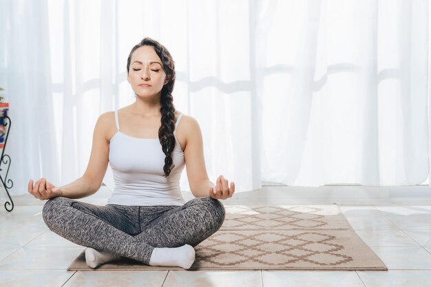 A Woman do Yoga indoors there is plenty of light