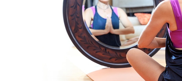 Женщина в позе йоги перед зеркалом