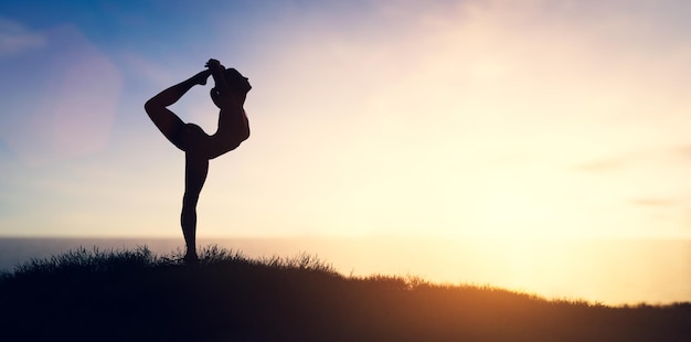 Woman in yoga pose zen meditation at sunset