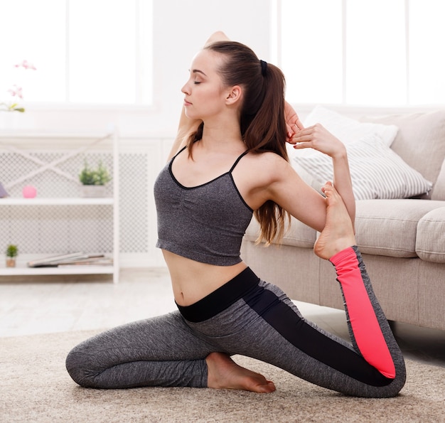 Woman yoga stretching at home mermaid pose