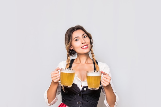 Woman young adult with beer mugs in his hands in a vest and white blouse clothes to Oktoberfest in the Studio