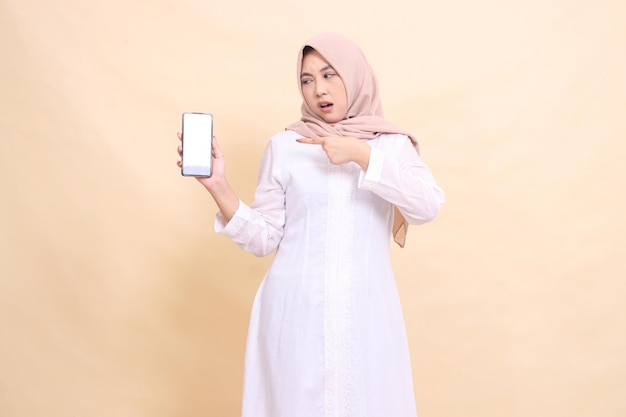 woman young asian muslim wearing a hijab candidly pouting holding her cell phone gadget to the right