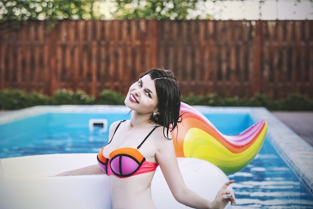 Женщина молодая красивая брюнетка в розовом купальнике в бассейне