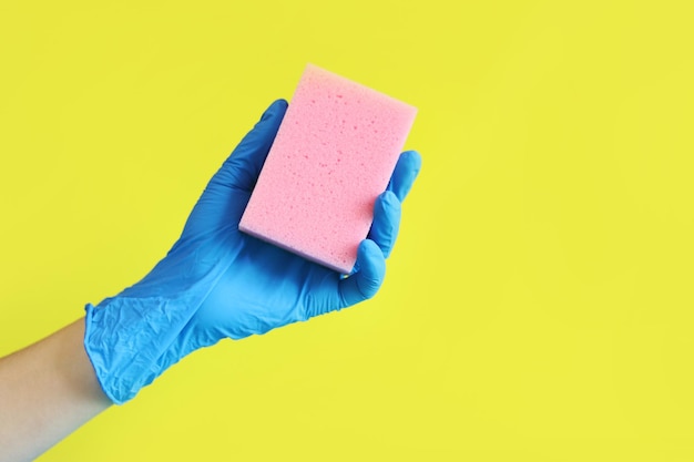 Photo a woman039s hand in a blue glove holds a sponge for washing dishes house cleaning