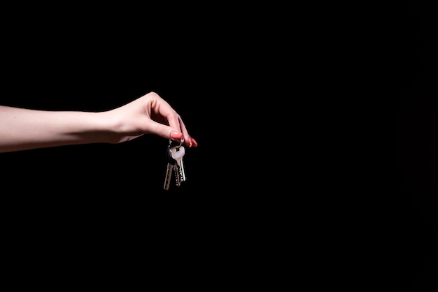 Фото Рука женщины 39 держит связку ключей от новой квартиры на черном фоне баннер свободного места для вашего текста