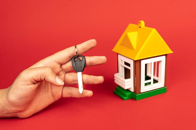 Woman39s hand met de sleutel van het huis en een model van het huis