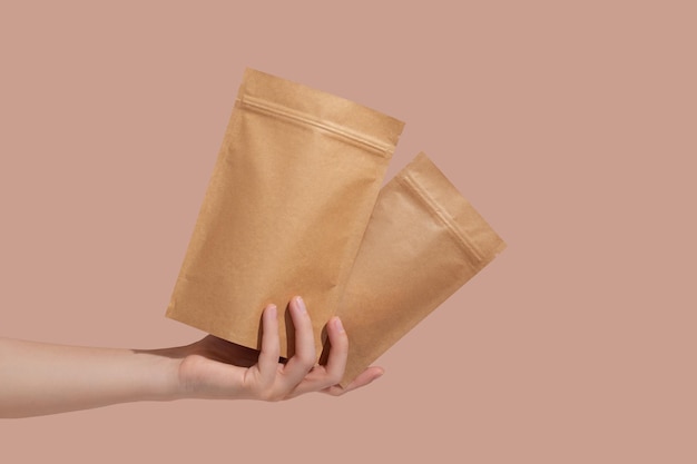 Woman39s hands hold cardboard packages for tea or snacks on a\
beige background tea branding and packaging mockup