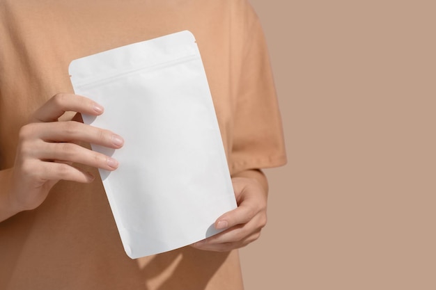 Woman39s hands hold cardboard packages for tea or snacks on a\
beige background tea branding and packaging mockup