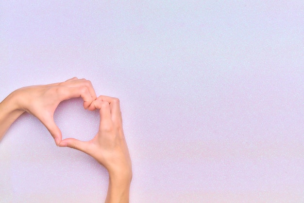 Woman39s hands making a heart gesture in the corner of the image with a bright white background