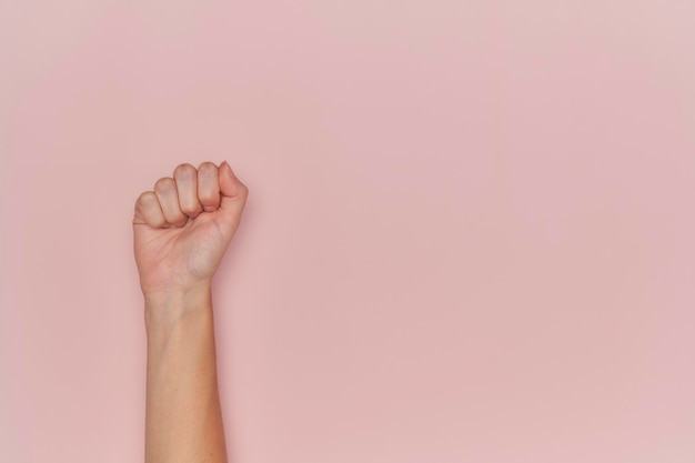 Woman39s vuist claimt feminisme platte roze achtergrond met kopieerruimte