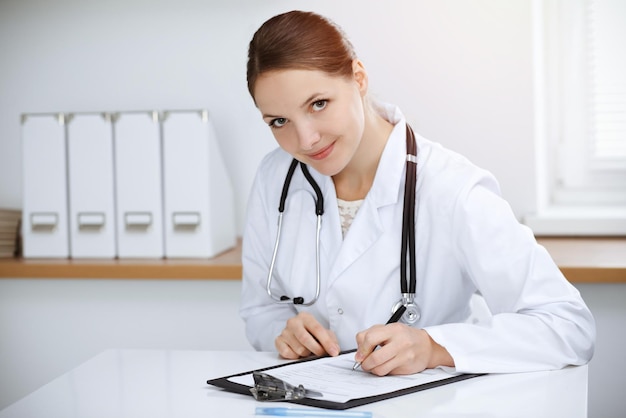 Womandoctor sitting and working in sunny clinic Portrait of female physician Medicine concept