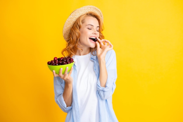 Foto womans godendo di una ciliegia dolce fresca picking mangiare frutta ciliegia femmina mangiare ciliegie su sfondo giallo