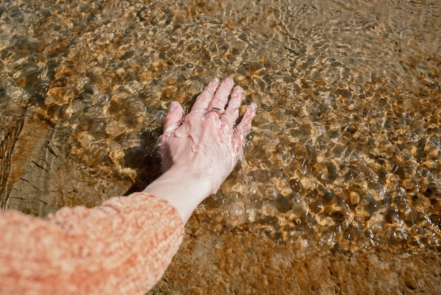La mano della donna nell'acqua fredda su un molo