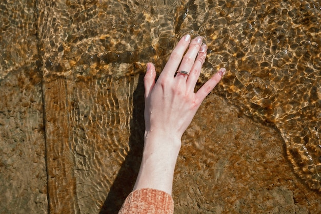 La mano della donna nell'acqua fredda su un molo