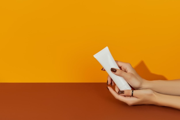 Женская рука держит косметику на оранжевом фоне с копировальным пространством