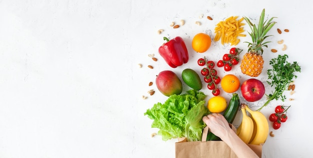 Womans hand holding a paper bag with healthy vegetarian