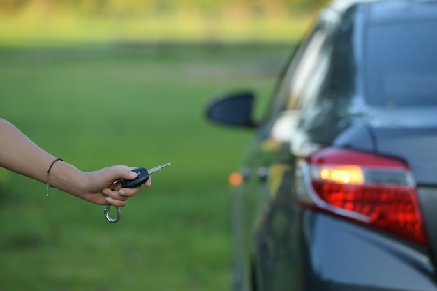 Womans hand holding remote control and about to open car door technology concept