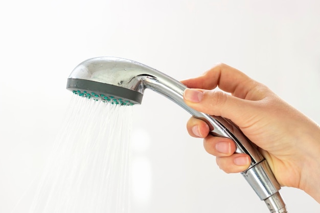 Womans hand holding a shower on a white background close-up