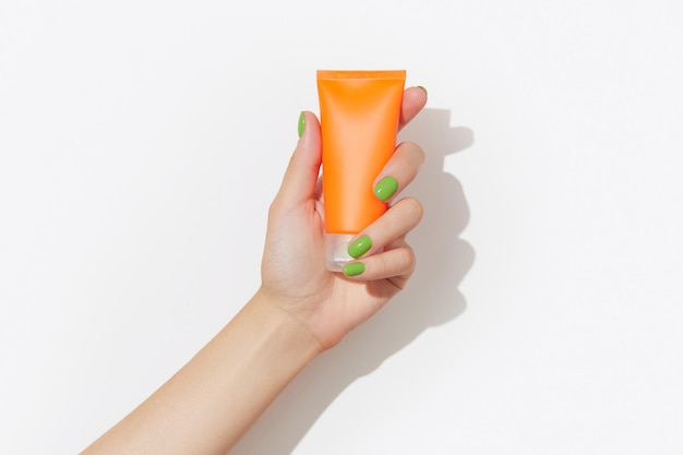 Womans hand holding sunscreen tube on white background self care beauty treatment concept