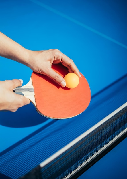 A womans hand holding a table tennis racket next to the net