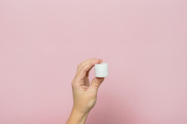 Photo womans hand holding white jar tube with cream ointment facial care bottle with cosmetic product without labeling