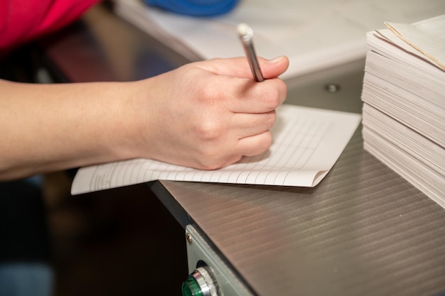 Foto la mano di una donna tiene una penna al suo posto di lavoro