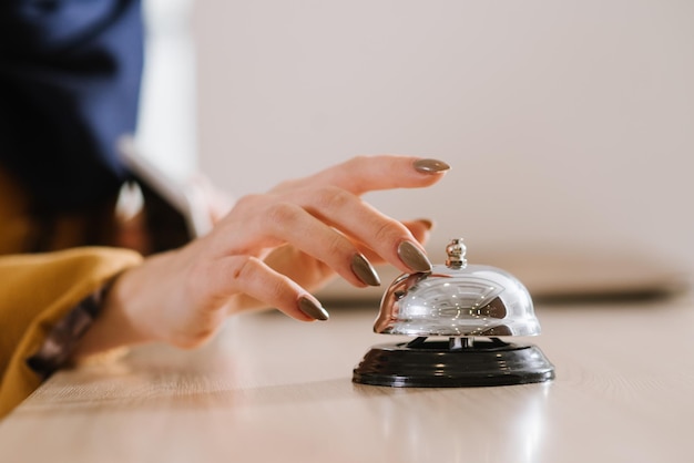 A womans hand on the hotel bell at the reception