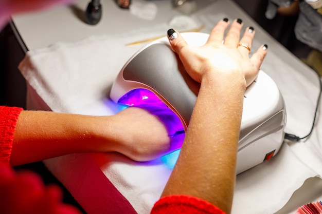 Womans hand in a lamp for manicure Dries nails after polishing