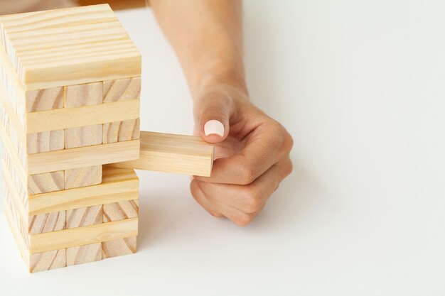 Womans hand makes wooden cubes on a white table