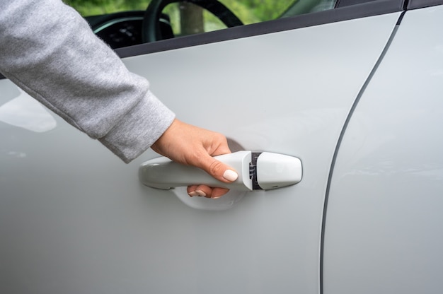 Womans hand opens white car door partial view of woman opening car door car unlocks