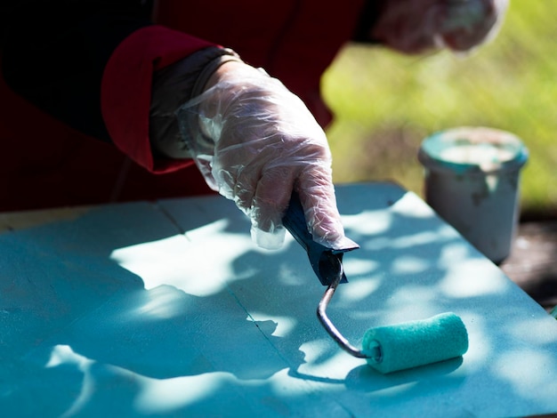 Foto la mano di una donna dipinge un foglio di compensato di colore turchese con un rullo