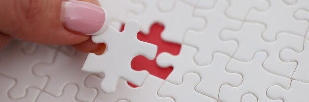 Womans hand placing last piece of puzzle on table closeup. Solving business problem concept