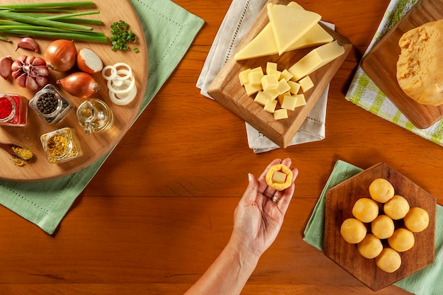 木製のテーブルの上にブラジルのチーズ詰めコロッケbolinhadequeijoを準備する女性の手上面図