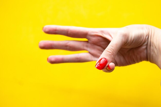 Foto la mano della donna mostra tre gesti su uno sfondo giallo brillante