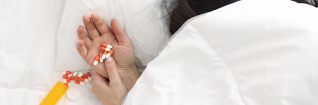 La mano della donna sporge da sotto le pillole della coperta giacciono sulla mano antidepressivi per le donne