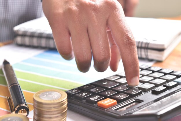 Womans hand using calculator with graph pen coins calculating concept