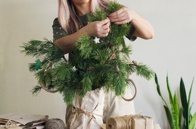 女性の手は、いくつかの針葉樹の枝を天然素材で作られた装飾品で飾ります