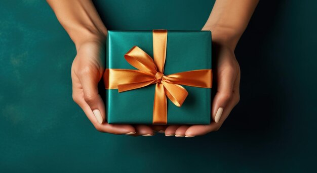 한 여성의 손은 르키즈색 배경 위에 선물 상자를 들고 있다.
