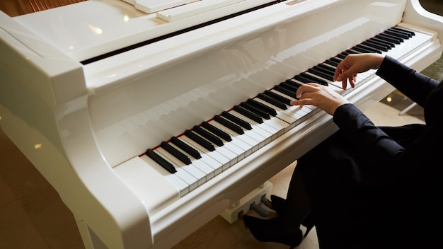 Womans hands on the keyboard of the piano closeup