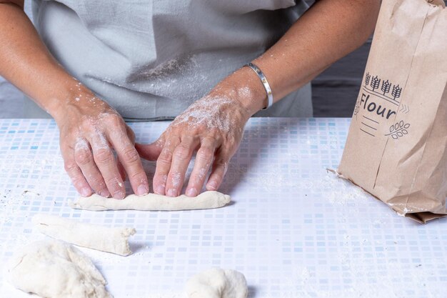 Foto mani di donne che fanno rotoli con l'impasto