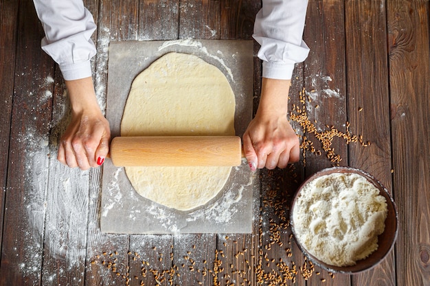 Womans hands roll out the dough